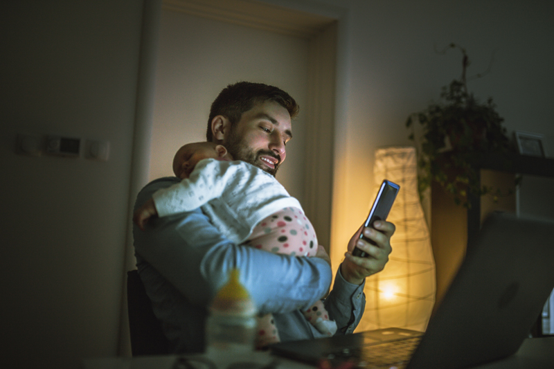 Man holding baby while looking at a phone