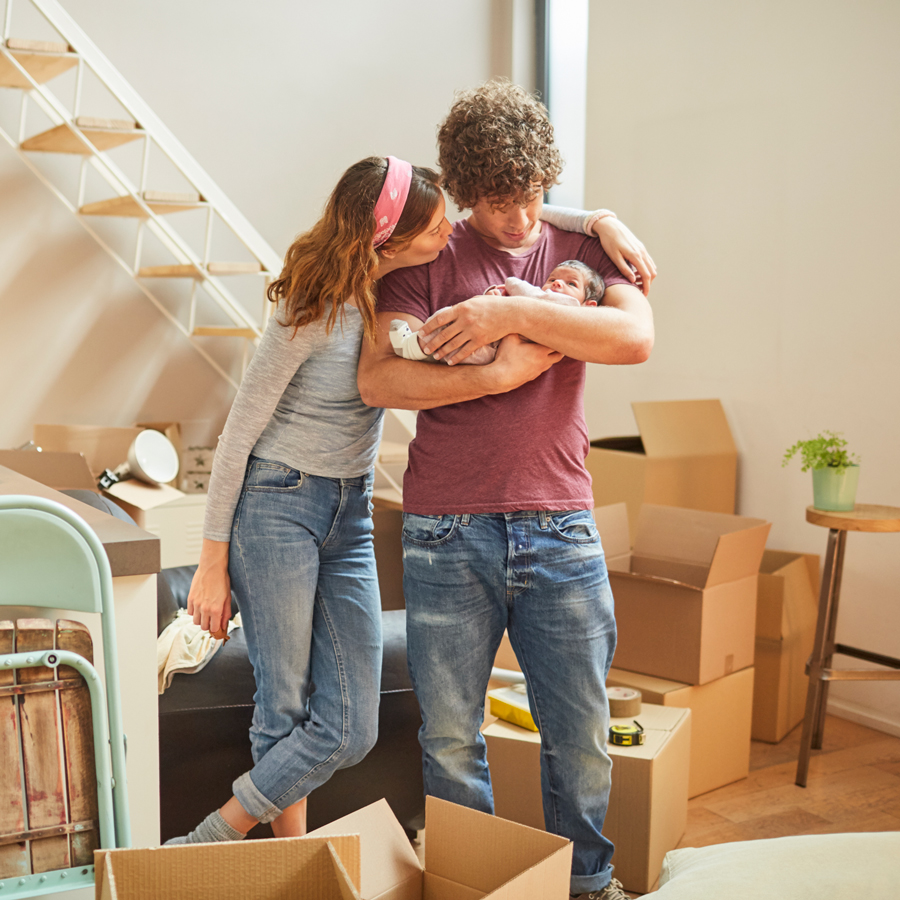 Young couple with baby surrounded by moving boxes