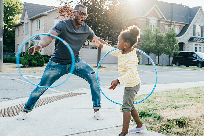 Father and daughter playing with hoola hoops outside