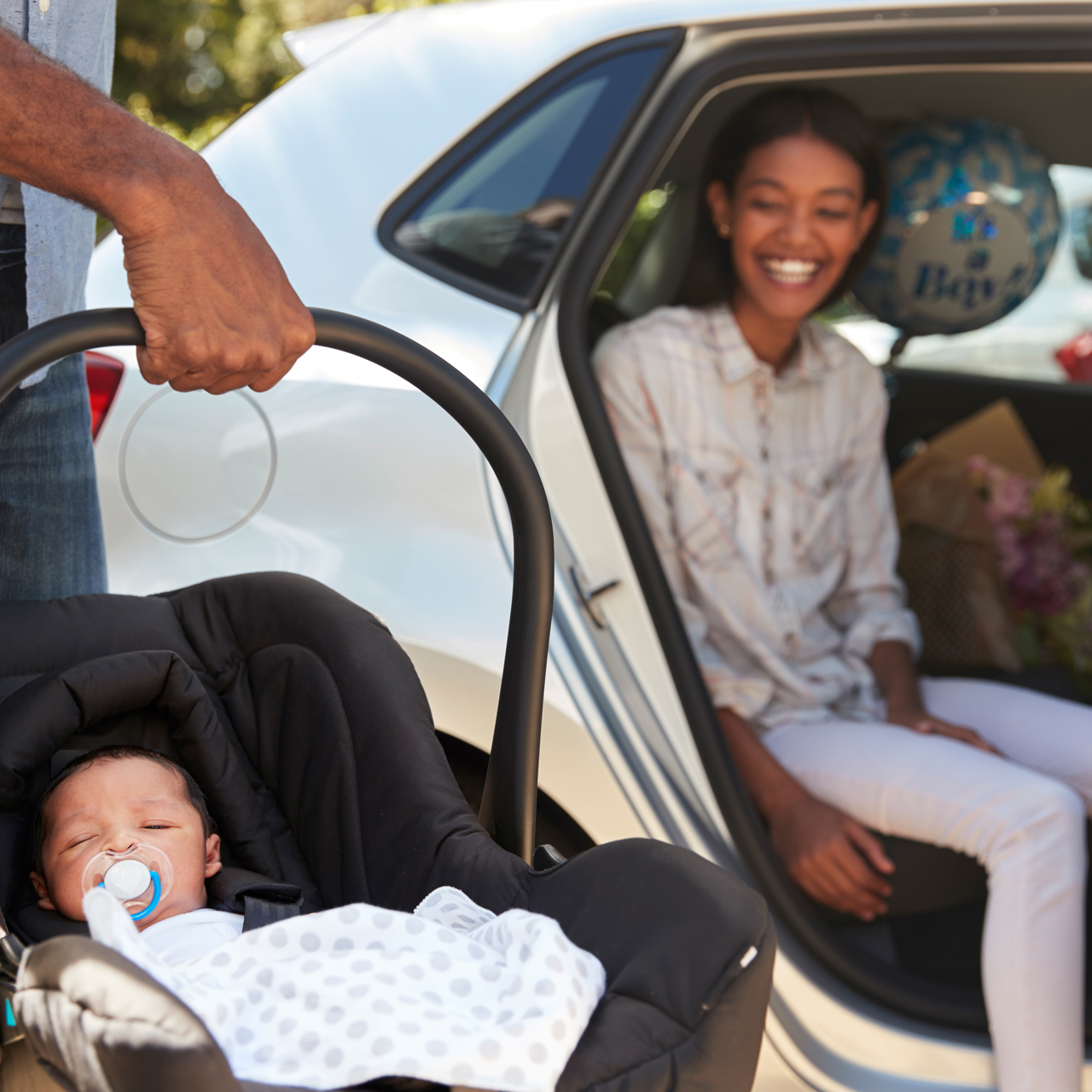 Girl in a car looking at baby in a car seat